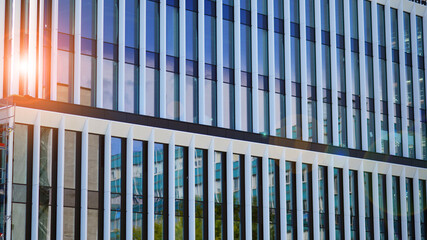 Glass modern building with blue sky background. View and architecture details. Urban abstract - windows of glass office building in  sunlight day.