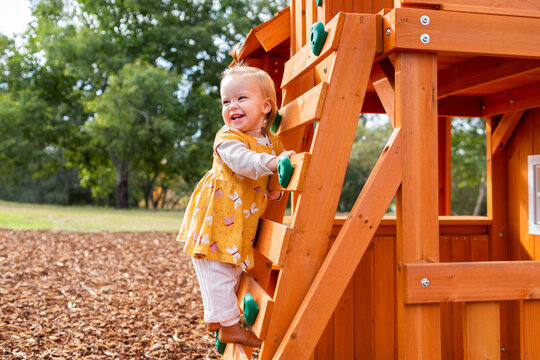 Happy baby climbing up ladder on wooden castle
