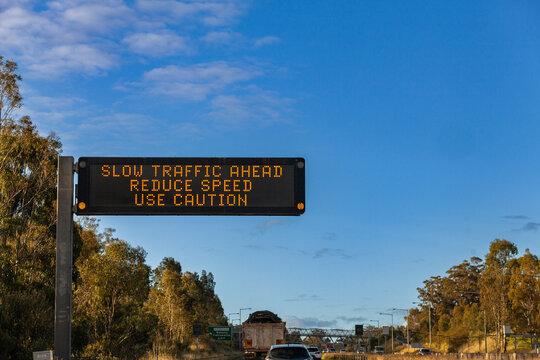 Digital sign over road warning of slow traffic ahead reduce speed use caution