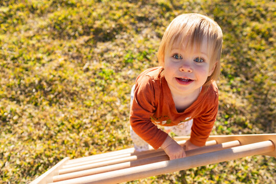 Toddler climbing up pikler triangle climbing frame in backyard