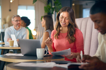 Mature Businesswoman Working On Laptop In Informal Seating Area Of Modern Office