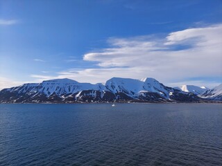 Architectural beauty against mountainous coastline with nautical vessel sailing on calm waters. a view from salbard longyearbyen norway