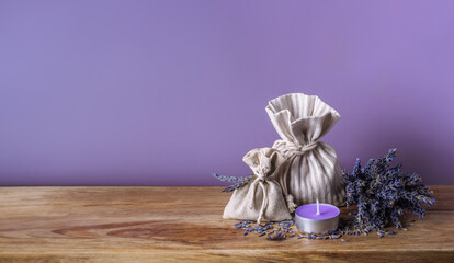 Dry lavender, bouquet of lavanda flowers, organic aromatic herbs in linen sachets and aroma candle on wooden table, aromatherapy collection in Provence style. Sack of fragrant lavand for spa flyer.