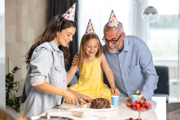 Mom cuts the cake for the birthday girl and her granddad