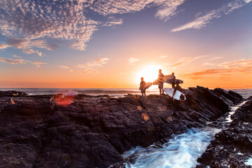 Surfers standing on Currumbin Rock at sunrise. Gold Coast Australia.