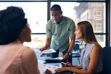 Fototapeta premium Multi-Cultural Business Team Meeting Around Office Boardroom Table With Laptops Discussing Documents