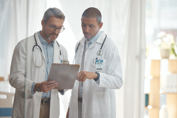 Teamwork, senior or doctors with checklist in hospital meeting or discussion for collaboration together. Leader, help or surgeons talking or speaking of healthcare schedule, report or data analysis