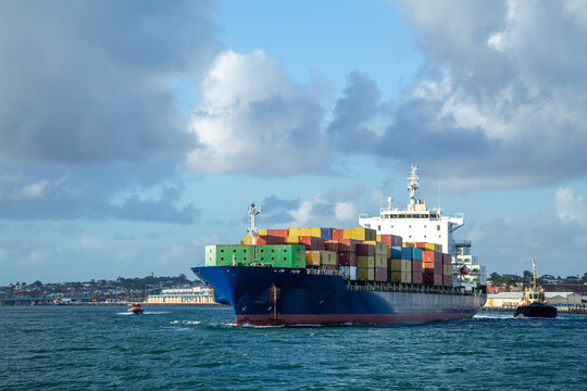 Blue hulled container ship departing port.