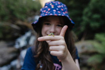 Happy young girl in a rainforest with a green caterpillar crawling on her finger