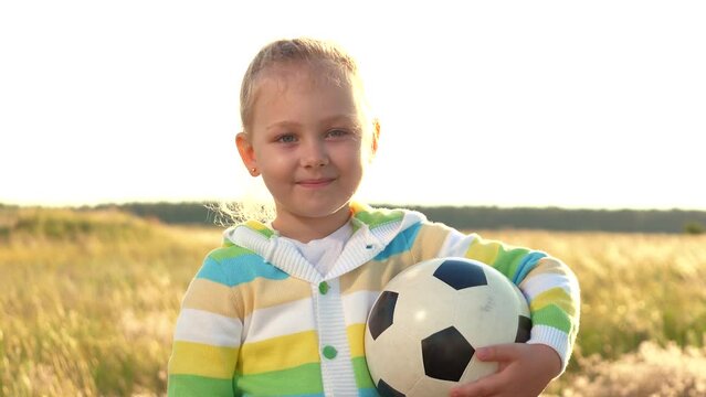 girl holding football. green field posing portrait smile face. she child enjoying game sunset. looking out beautiful nature. surrounding activity takes place school sports bring joy funny sportsman