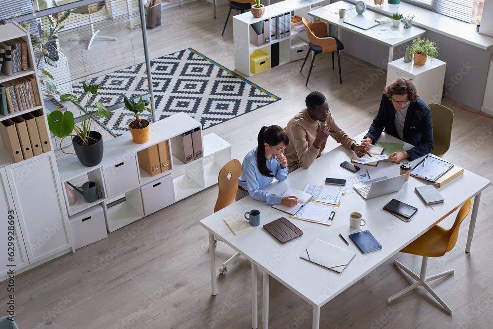 Aufkleber wide angle top view of business team working together at meeting table in office and pointing at doc