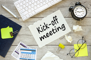 Kick-off meeting Message. text on torn paper on wooden background near white keyboard