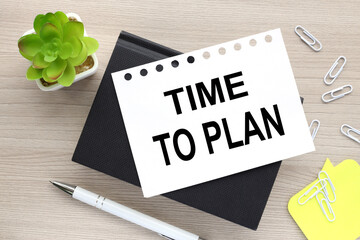 the words time to plan on a white page on a black notepad