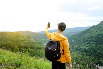 man with backpack taking selfie with mobile smart phone hiking mountains. Tourist looking at...