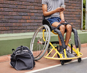 Obraz premium Sports, wheelchair basketball and a man with a disability on a court for fitness, training or competition. Phone, legs and exercise with a male athlete outdoor for a workout as a game player