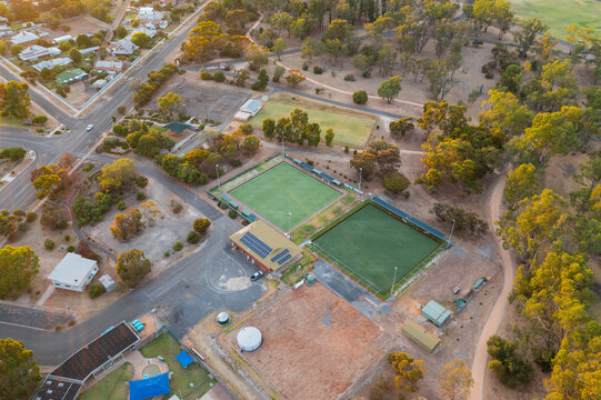 Aerial view of bowling greens and a recreation area on the edge of a rural town