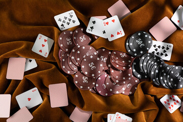 Red and black poker chips are scattered on the brown fabric, and small playing cards are scattered around.