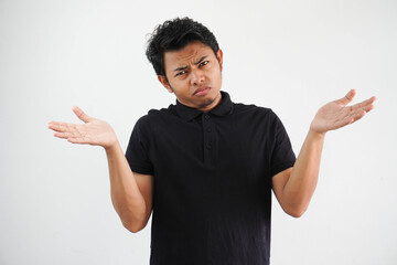 Portrait of handsome young asian man confused puzzled man shrugging shoulders wearing black polo t shirt isolated over white background
