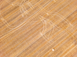 Mysterious lines and traces on harvested stubble field with straw bales