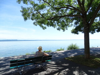 se&ntilde;ora sentada y relajada en un banco delante de el lago con monta&ntilde;as de fondo, en suiza