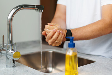 Man washing hands with soap in a sink at his home