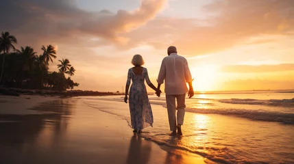 Foto op Canvas Old couple walking hand in hand on a tropical beach at sunset © IB Photography