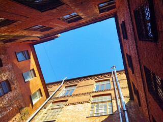 Retro facade of old red brick building and blue sky on a sunny day. Bright view with antique...