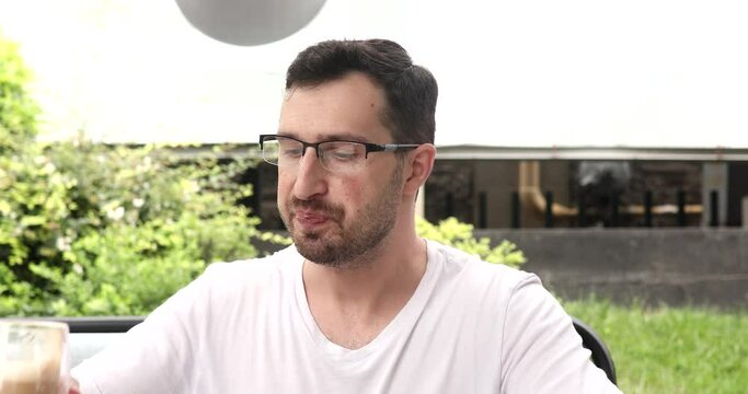 Confident young man dinking coffee and opens and starts using laptop.