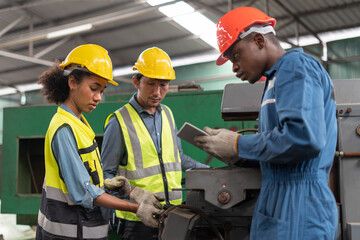 group of diversity African American industrial Engineer manager woman discussion with asian repair man mechanic worker man using tablet checking machinery in industry manufacturing large factory .