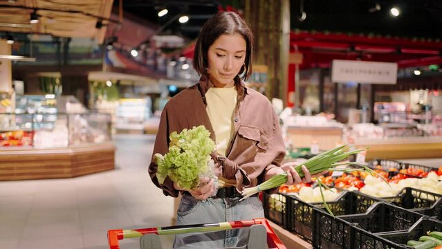Woman determined with choice of vegetable puts in shopping cart