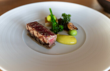 Wagyu cut with broccoli and mustard on a white plate in gastronomic restaurant