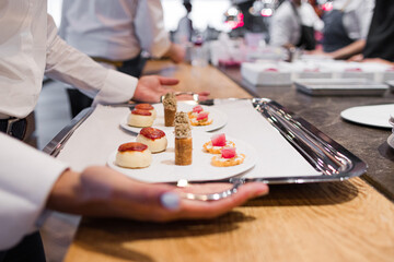 Photo of the hands of a waitress taking the tray of food from a gastronomic restaurant to bring it to the customers.