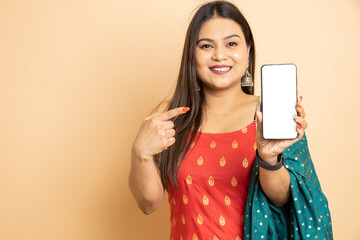 Happy young beautiful indian woman wearing traditional outfit holding smart phone with blank...