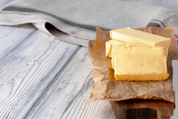 Cut butter on plate with blue towel on kitchen table