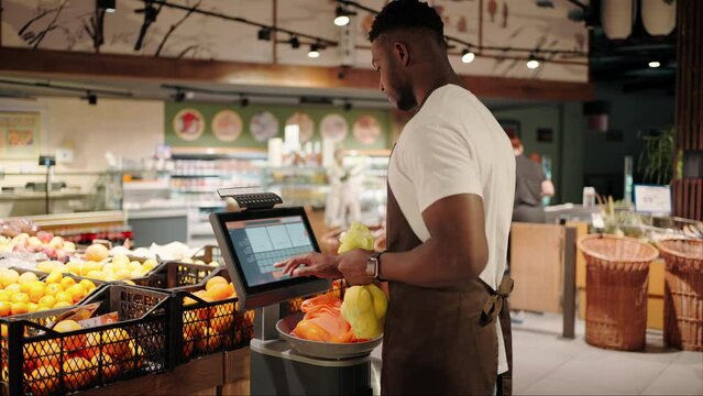 African American weighs citrus on electronic scales in store
