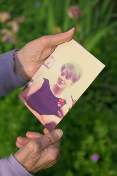 Senior woman holding picture of herself as young woman