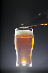 Beer pouring into glass on black background