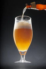 Beer pouring into glass on black background