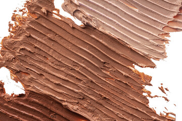 Smears of dark cream cosmetic foundation isolated on white