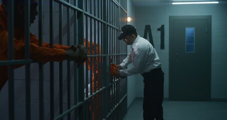 Warden brings new prisoner in jail cell and takes off his handcuffs. African American criminals...