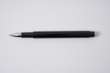 Black ballpoint pen with a cap on a white isolated background.