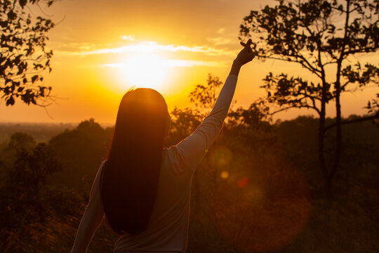 women show hand standing mountain for successful with beautiful sunset. silhouette image female hand up freedom life during sunrise.
