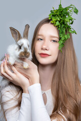 Portrait of a rural girl with a bunch of parsley on her head and a rabbit.