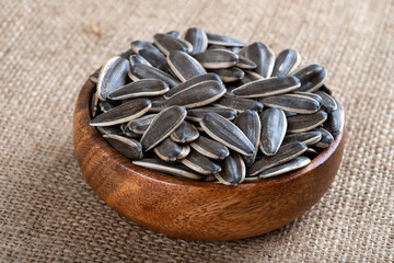 Black sunflower seeds in a bowl on burlap sack