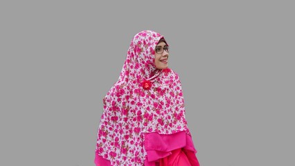 Close up portrait of smiling young Muslim woman wearing long hijab with red rose flower motif looking to her left. Happy and cheerful expression.