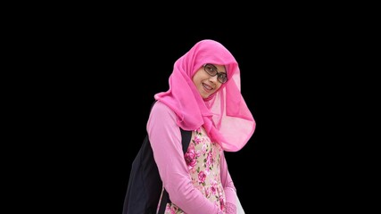 Close up portrait of smiling young Muslim woman wearing pink hijab and dress with red rose flower motif and black backpack. Happy and cheerful expression.