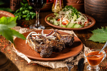 Turkish cuisine, roasted lamb on the bone with onions on a brown plate on a dark background.