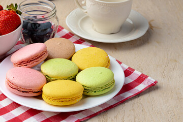 French macaroon cookies of bright colors served in white ceramic plate