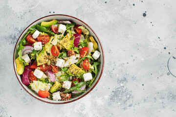 Delicious and healthy green salad of different leaves and vegetables with seeds and olive oil.