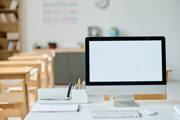 Close-up of modern workplace of teacher with computer in empty classroom